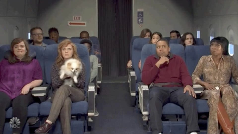 Screenshot from "SNL" of people sitting on a plane