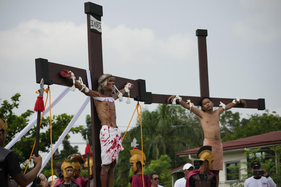 Wilfredo Salvador, left, stays on a cross during a reenactment of Jesus Christ's sufferings as part of Good Friday rituals April 7, 2023 in the village of San Pedro, Cutud, Pampanga province, northern Philippines. The real-life crucifixions, a gory Good Friday tradition that is rejected by the Catholic church, resumes in this farming village after a three-year pause due to the coronavirus pandemic.(AP Photo/Aaron Favila)