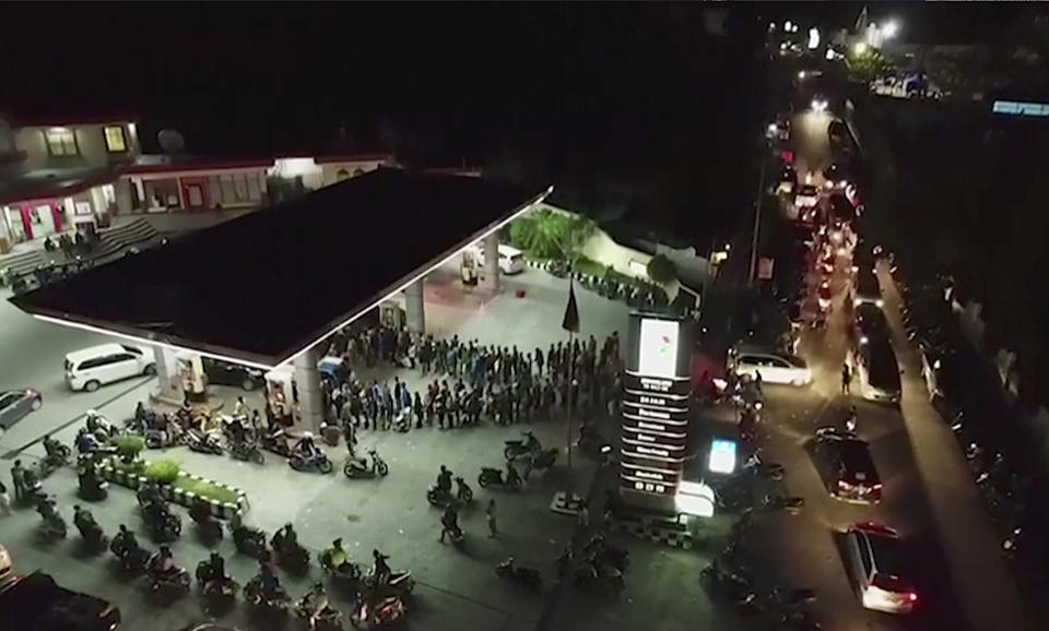 In this image made from drone video footage Tuesday, Oct. 2, 2018, long queues lead out from a petrol station in the earthquake and tsunami-devastated area of Palu, Central Sulawesi, Indonesia. Aid was slowly making its way into areas devastated by the earthquake and tsunami that struck a central Indonesian island, with one neighborhood’s residents clapping, cheering and high-fiving in their excitement Wednesday at seeing a stopped truck laden with supplies. (AP Photo)