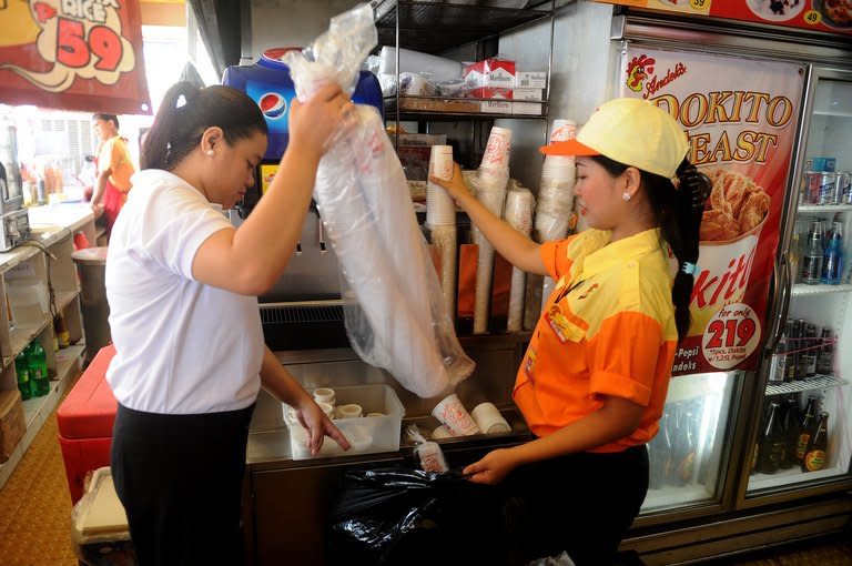 Employees of a fast food store put plastic cups into a trash bag, in Manila's financial district Makati City, on June 20, 2013. Makati City has banned disposable plastic shopping bags and styrofoam food containers as part of escalating efforts across the nation's capital to curb rubbish that exacerbates deadly flooding