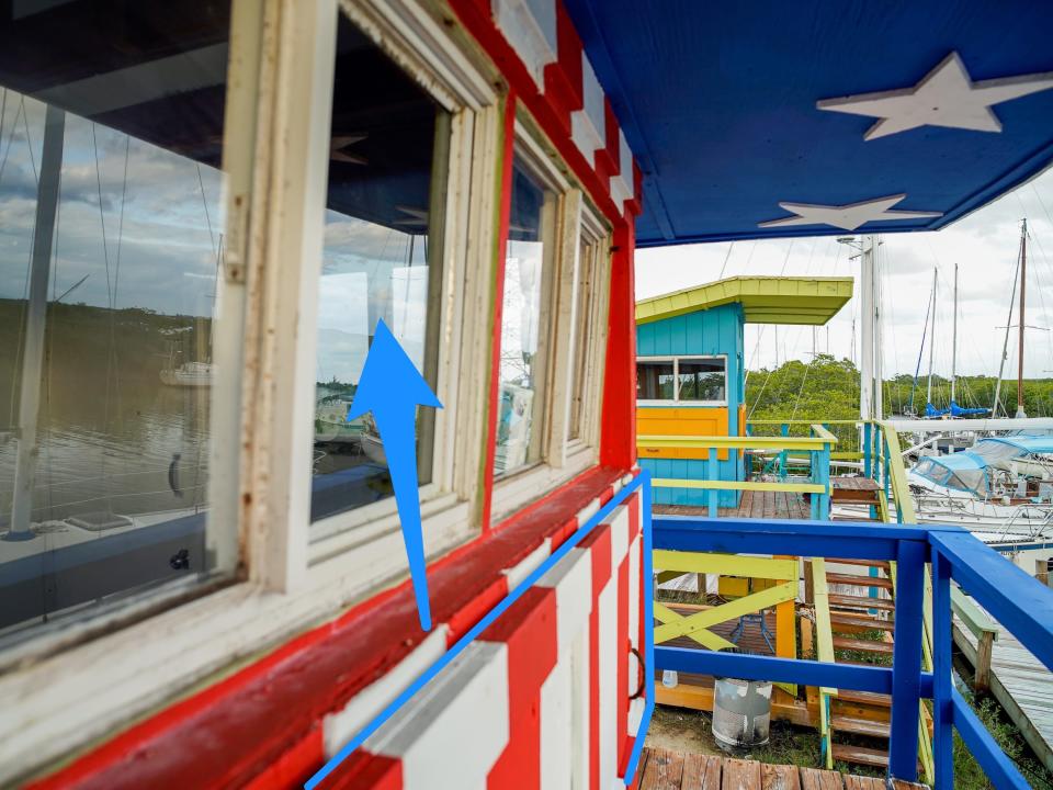 A blue arrow points from the shutters of the tower up to the windows. Another tower is seen in the background on a cloudy day