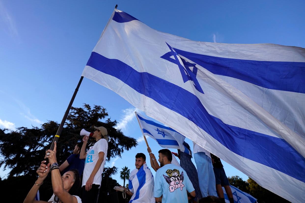 Protesters wave Israeli flags during a rally in support of Israel. Demonstrations such as this have been occurring in many countries across the globe since the Oct. 7 attack on Israel.