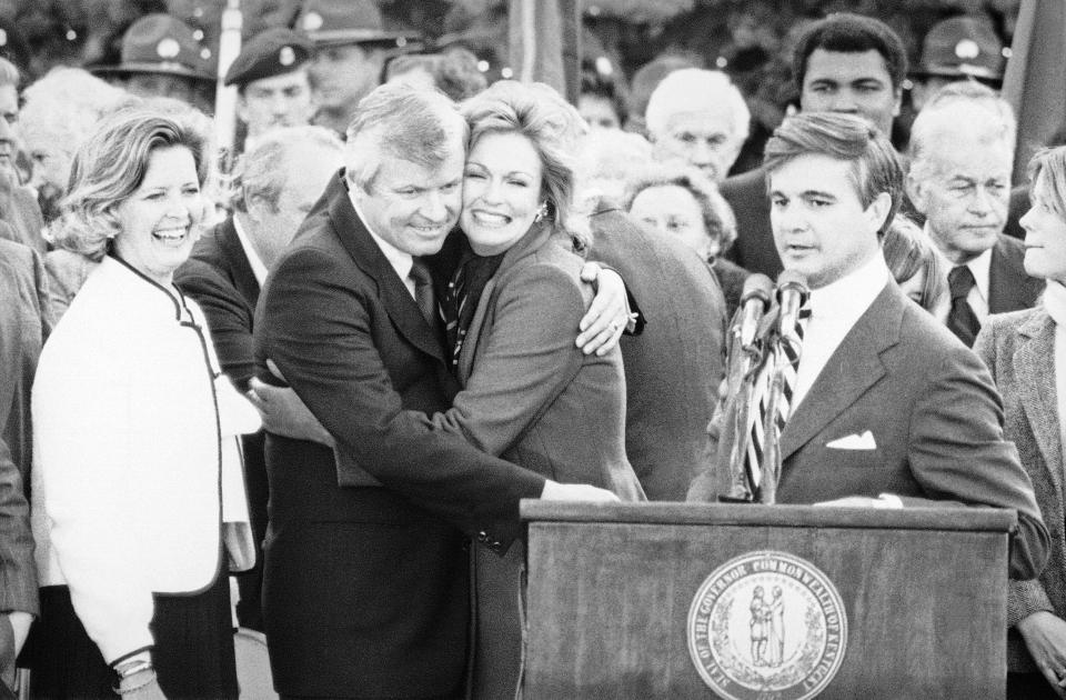 FILE - Kentucky Gov. John Y. Brown Jr., second from left, hugs his wife, Phyllis George, after being sworn in as the 55th chief executive of the Commonwealth in Frankfort, Ky., on Dec. 11, 1979. Brown Jr., who became Kentucky’s governor after building empires in business and sports, has died, his family said in a release Tuesday, Nov. 22, 2022. He was 88. (AP Photo/File)