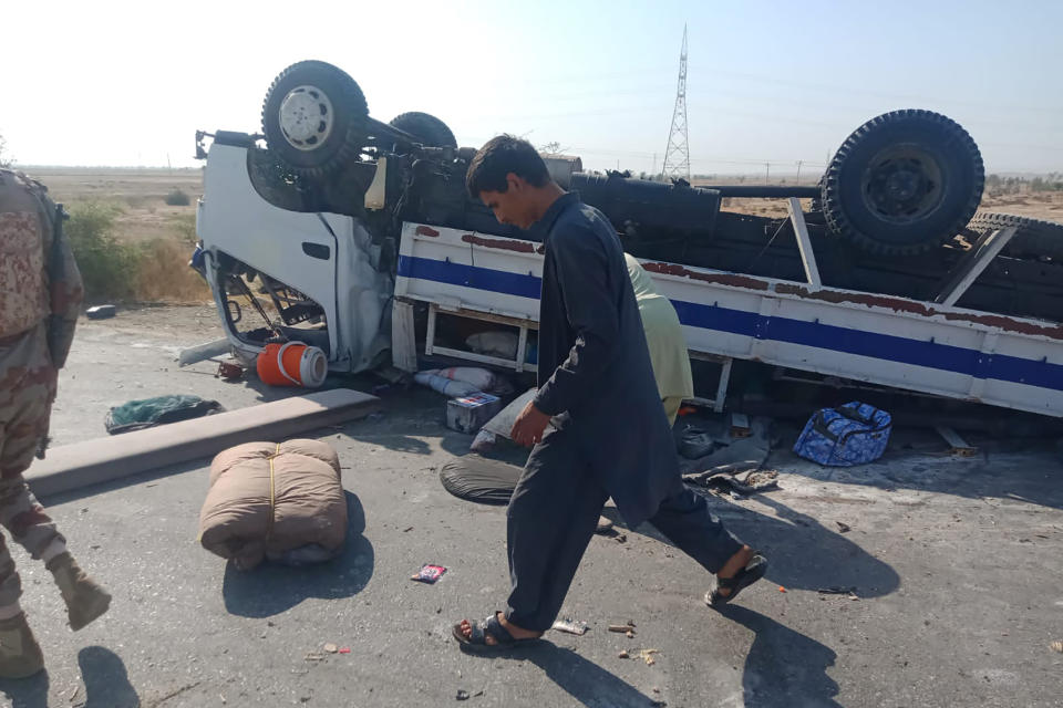 A paramilitary soldier and volunteers gather at the site of a suicide bombing, in Sibi, a district in the Pakistan's Baluchistan province, Monday, March 6, 2023. A suicide bomber riding on a motorcycle rammed into a police truck in Pakistan's restive southwest, killing and wounding police officers in one of the deadliest attacks on security forces in recent months, authorities said. (AP Photo/Saeed-ud-Din)