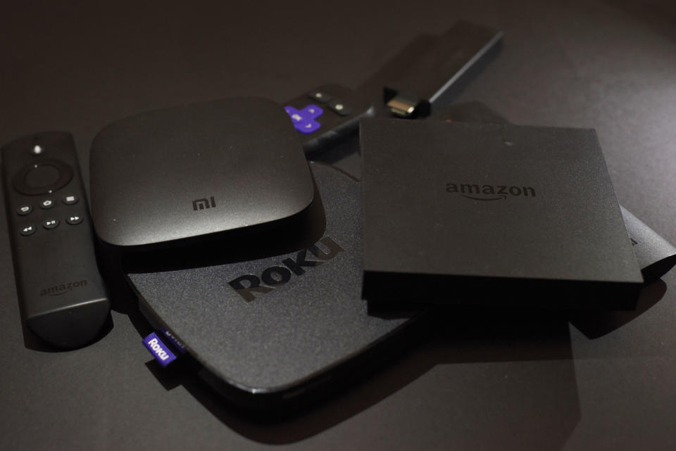 FILE - This Nov. 16, 2016, photo shows Xiaomi's Mi Box, left, the Roku Premiere, center, and the Amazon Fire TV streaming TV devices in New York. An outside search aid such as Roku, Reelgood, Decider and JustWatch can help scan multiple services to see which ones have the titles you want to watch. (AP Photo, File)