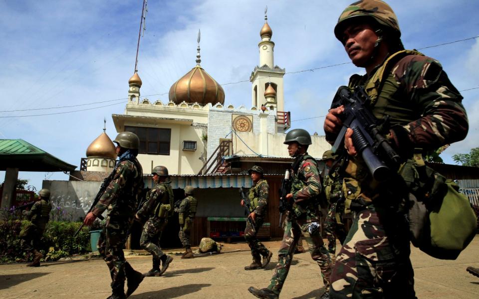 Government troops walk past a mosque before their assault with insurgents from the so-called Maute group, who have taken over large parts of Marawi City - Credit: ROMEO RANOCO / REUTERS