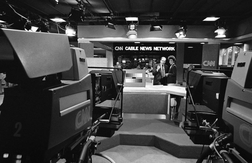 Reese Schonfeld, president of Cable News Network, and Reynelda Muse, weekend anchorwoman for CNN, stand at one of the many sets at the broadcast center in Atlanta on May 31, 1980. | Joe Holloway, Associated Press