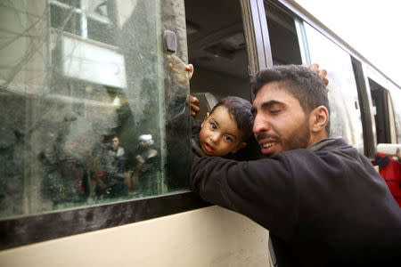 A man reacts as he hugs a child during evacuation in the besieged town of Douma, Eastern Ghouta, in Damascus, Syria March 19, 2018. REUTERS/Bassam Khabieh