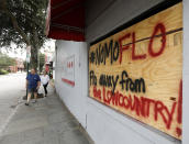 Michael and Polly Long walk down East Bay St. past a sign asking for Hurricane Florence to spare the Lowcountry in Charleston, S.C., as Hurricane Florence spins out in the Atlantic ocean Thursday, Sept. 13, 2018. (AP Photo/Mic Smith)