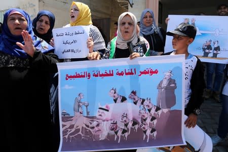 Palestinian woman holds a banner showing a caricature of Arab leaders during a protest against Bahrain's workshop for U.S. Middle East peace plan, in the southern Gaza Strip