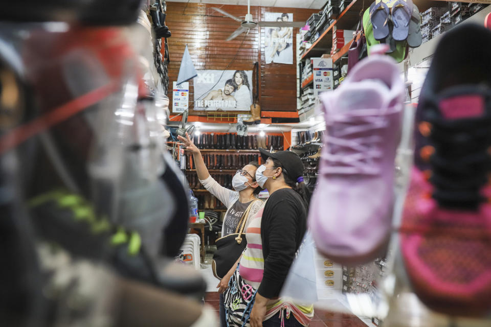 Customers, wearing protective face masks, shop at at a popular market in Managua, Nicaragua, Tuesday, April 7, 2020. Restaurants are empty, there's little traffic in the streets and beach tourists are sparse headed into Holy Week despite the government's encouragement for Nicaraguans to go about their normal lives. (AP Photo/Alfredo Zuniga)