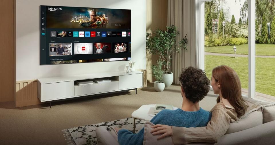 Two people on a sofa watching a wall-mounted TV