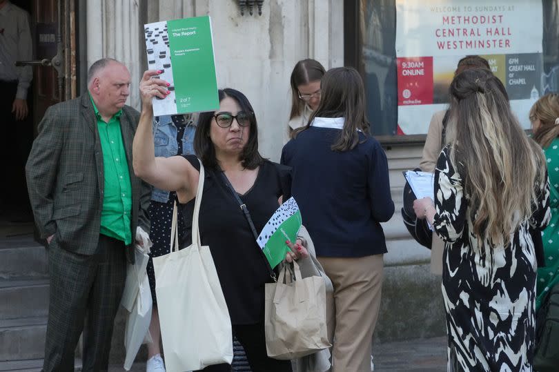 People hold up the Infected Blood Inquiry report outside Central Hall in Westminster, London, after it's publication.