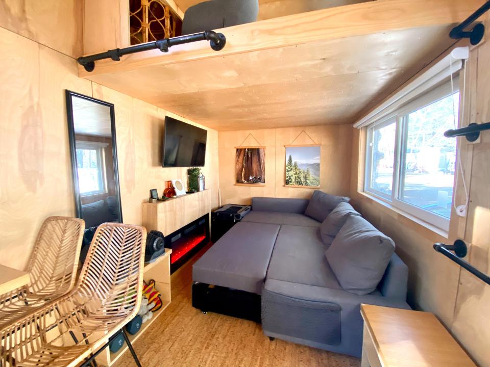 Interior of tiny house with wood walls and extended gray couch