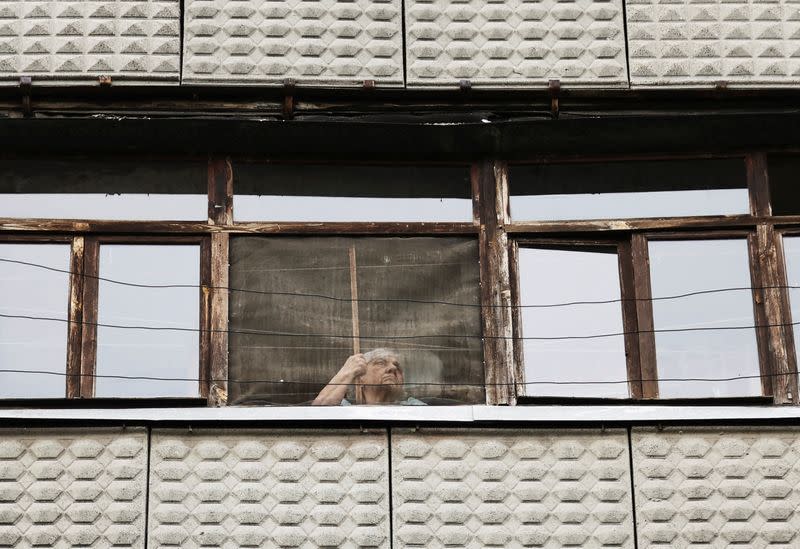 A woman looks out through the window of her house in Kramatorsk