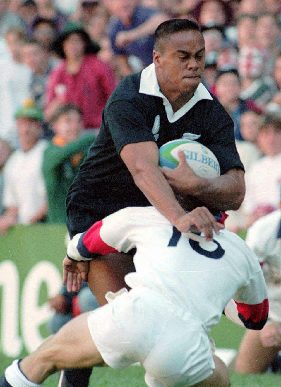 FILE - In this June 18, 1995 file photo, New Zealand All Blacks winger Jonah Lomu charges through an attempted tackle by England's fullback Mike Catt on his way to score the opening try in the Rugby World Cup semifinal at Newlands in Cape Town, South Africa. One trampling run launched Jonah Lomu to global stardom and ensured his name will be indelibly linked to a Rugby World Cup semifinal between New Zealand and England. The All Blacks winger’s rampaging runs during that era-defining World Cup in South Africa in 1995 were highlighted by his four-try haul against England in the semifinals. New Zealand and England meet again in the semifinals this Saturday, Oct. 26, 2019, at Yokohama. (AP Photo/Ross Setford, File)