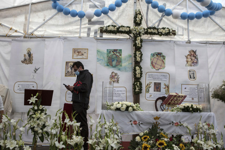 Rev. Adrian Vazquez checks his cell phone after officiating an outdoor Mass backdropped by a makeshift altar constructed by devotees, just outside the quake-damaged Our Lady of the Angels Catholic church, in Mexico City, Sunday, Aug. 7, 2022. Vazquez was assigned to the parish in 2019 and tasked with leading what he called a “comprehensive recovery” of the parish, both physically and as a spiritual community. Since the building was damaged in the Sept. 19, 2017 earthquake, many parishioners began attending other churches. (AP Photo/Ginnette Riquelme)