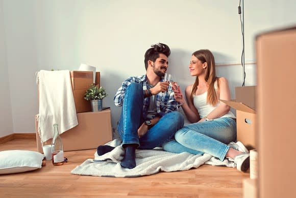 Couple on floor surrounded by moving boxes.