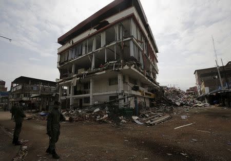 Soldiers stand guard next to a collapsed buildings at the village of Manta, after an earthquake struck off Ecuador's Pacific coast, April 21, 2016. REUTERS/Henry Romero