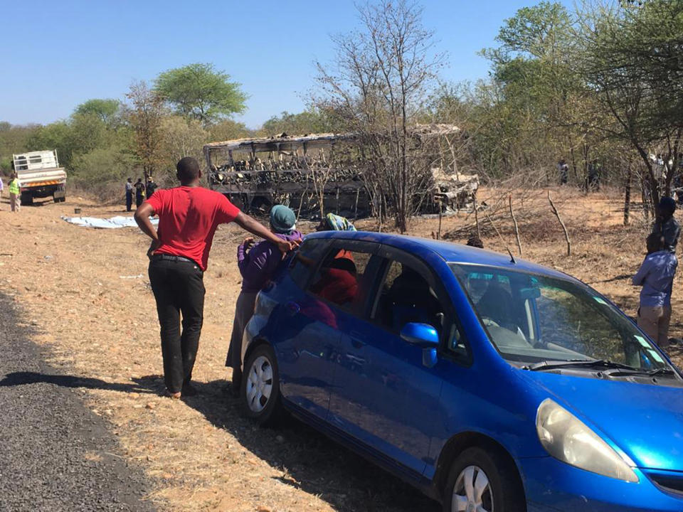 Spectators look at a burnt out bus after a bus accident in Gwanda about 550 kilometres south of the capital Harare, Friday, Nov. 16, 2018. Police in Zimbabwe say more than 40 people have been killed in a bus accident on Thursday night. (AP Photo)