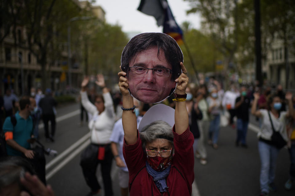 A woman holds a cardboard cut out of the head of former Catalan leader Carles Puigdemont during a protest in support of Puigdemont outside the Italian consulate in Barcelona, Spain, Friday, Sept. 24, 2021. Puigdemont, who fled Spain after a failed secession bid for the northeastern region in 2017, was detained Thursday in Sardinia, Italy, his lawyer said. Puigdemont, who lives in Belgium and now holds a seat in the European Parliament, has been fighting extradition to Spain, which accused him and other Catalan independence leaders of sedition. (AP Photo/Joan Mateu)