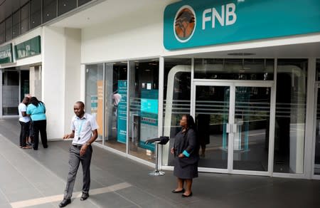 First National Bank (FNB) staff members stand outside their bank to notify customers that the bank is closed due to load shedding, at the mall of the south in Johannesburg