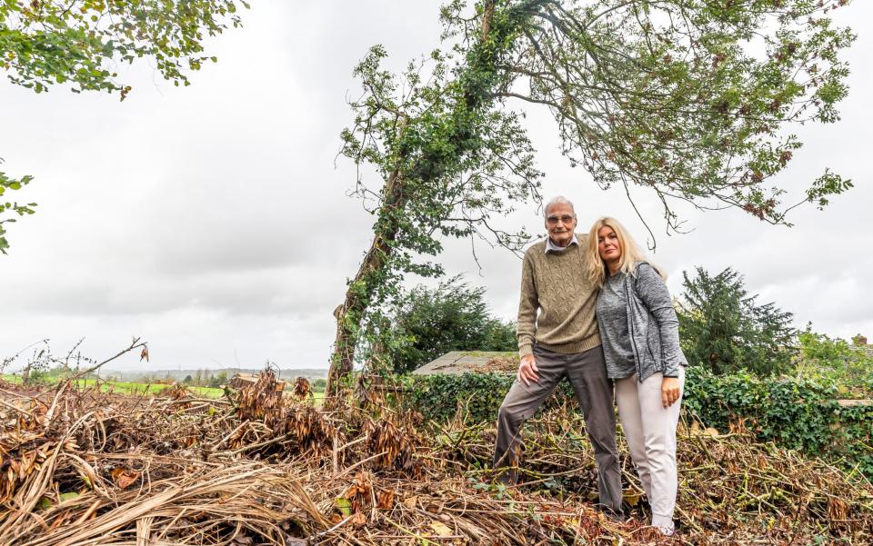Gerrard Hayes and his neighbour Jackie Bonham, looking at one of his trees that got hacked before he brought a stop to it, standing on waste tree surgeons left behind