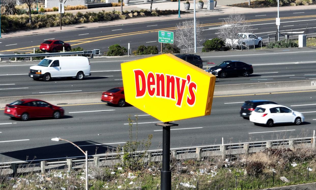 Cars drive by a sign posted in front of a Denny's restaurant on February 13, 2023 in Emeryville, California.