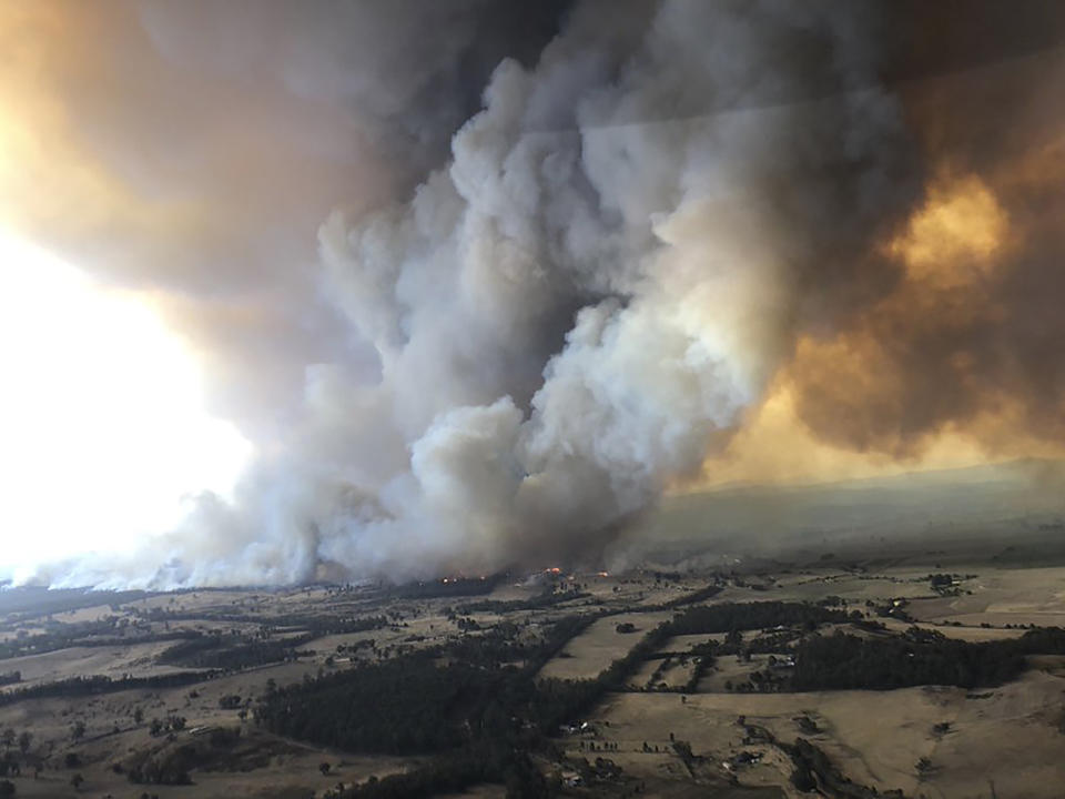 In this Monday, Dec. 30, 2019, aerial photo, wildfires rage under plumes of smoke in Bairnsdale, Australia. Thousands of tourists fled Australia's wildfire-ravaged eastern coast Thursday ahead of worsening conditions as the military started to evacuate people trapped on the shore further south. (Glen Morey via AP)