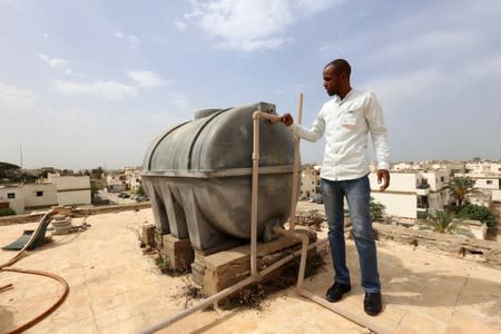 Man checks a water tank during a water shortage in Tripoli