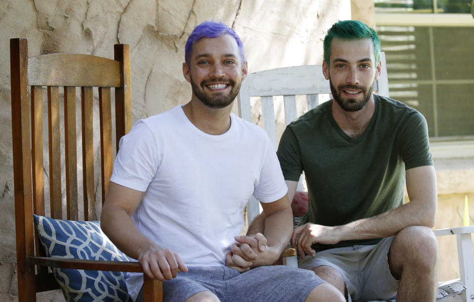 In this Monday, March 30, 2020, photo Luke Blaine, left, with partner Kyle Schomer, right, sit on the porch at their home in Phoenix. Blaine, 30, a bartender at Fez, a popular restaurant in downtown Phoenix, was laid off with the rest of the staff when the business shut completely to follow Arizona’s state precautions amid the pandemic. Schomer, who’s also 30, works from home in technology, and shares the rent in a stylish neighborhood of small adobe-style homes. (AP Photo/Ross D. Franklin)