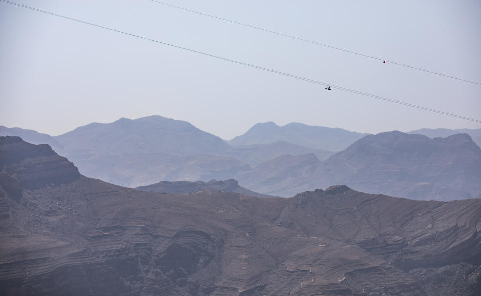 person sliding down Jebel Jais Mountain via world's longest zip line.
