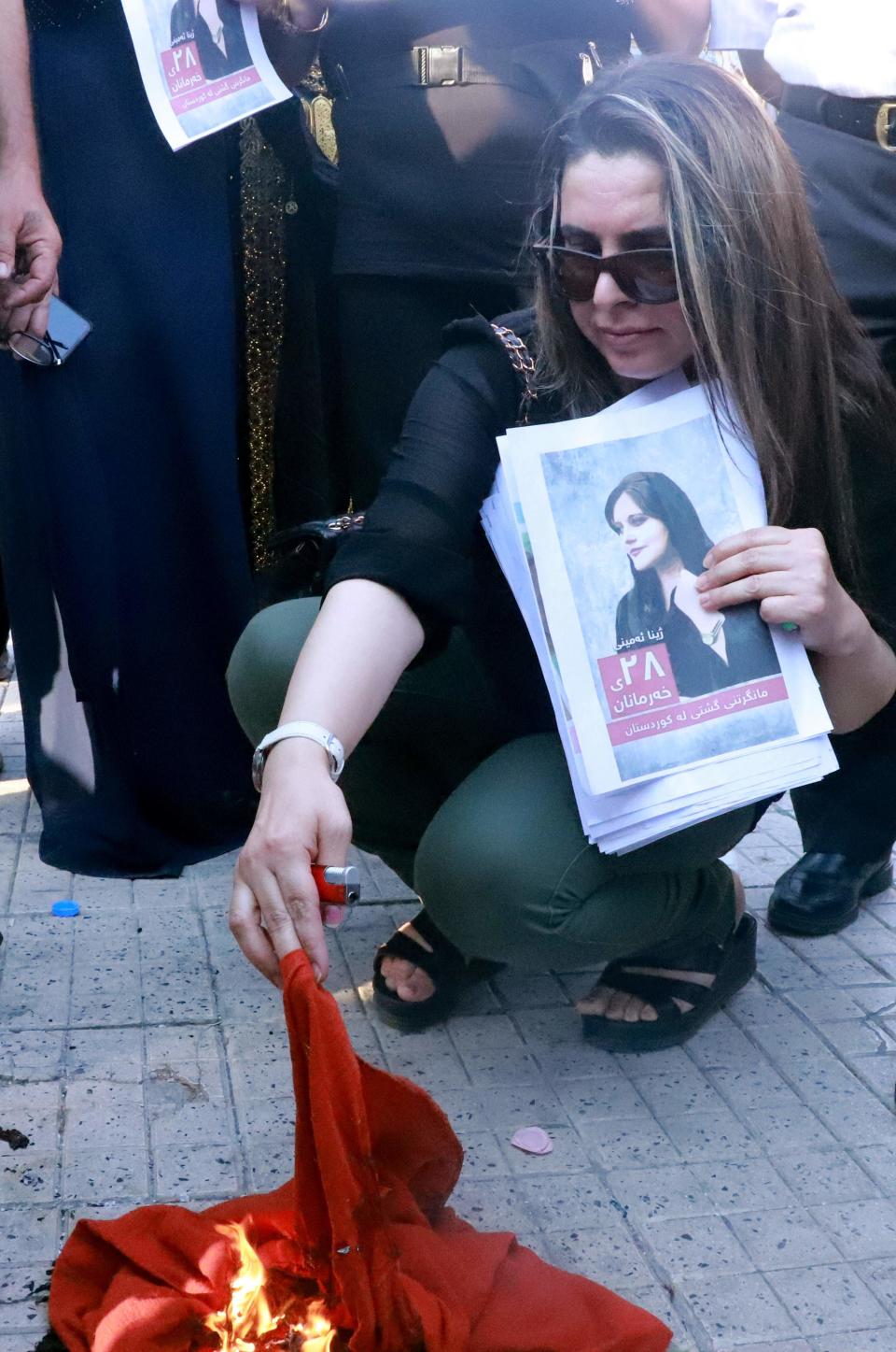 Iranian Kurds set a headscarf on fire during a march in a park in the Iraq Kurdish city of Sulaimaniya on September 19, 2022, against the killing of of Mahsa Amini, a woman in Iran who died after being arrested by the Islamic republic's &quot;morality police&quot;.