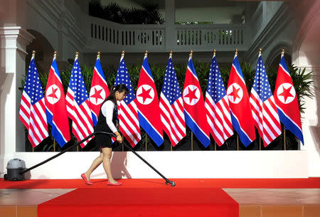 A worker vacuums the stage at the spot where U.S. President Donald Trump and North Korea's leader Kim Jong Un are expected to meet and shake hands for the first time at the start of their summit at the Capella Hotel on Singapore's resort island of Sentosa in Singapore June 12, 2018. REUTERS/Jonathan Ernst