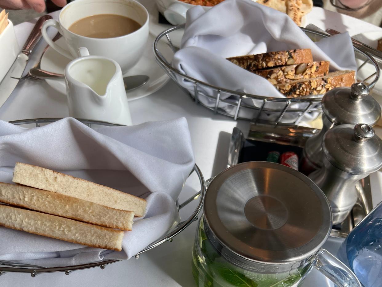 Table setting with green beverage, toast on a plate, coffee, and baskets of bread