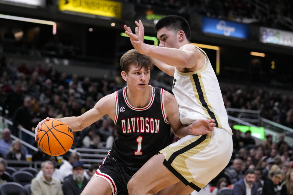 Davidson guard Reed Bailey (1) attempts to drives around Purdue center Zach Edey (15) in the second half of an NCAA college basketball game in Indianapolis, Saturday, Dec. 17, 2022. Purdue defeated Davidson 69-61. (AP Photo/Michael Conroy)