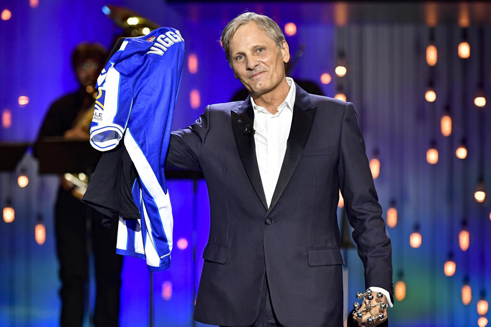 US actor and film director Viggo Mortensen, smiles while holds up a T-shirt of Real Sociedad soccer team with his name after receiving the Donostia Award for his contribution to the cinema during the 68th San Sebastian Film Festival, in San Sebastian, northern Spain, Thursday, Sept. 24, 2020. (AP Photo/Alvaro Barrientos)