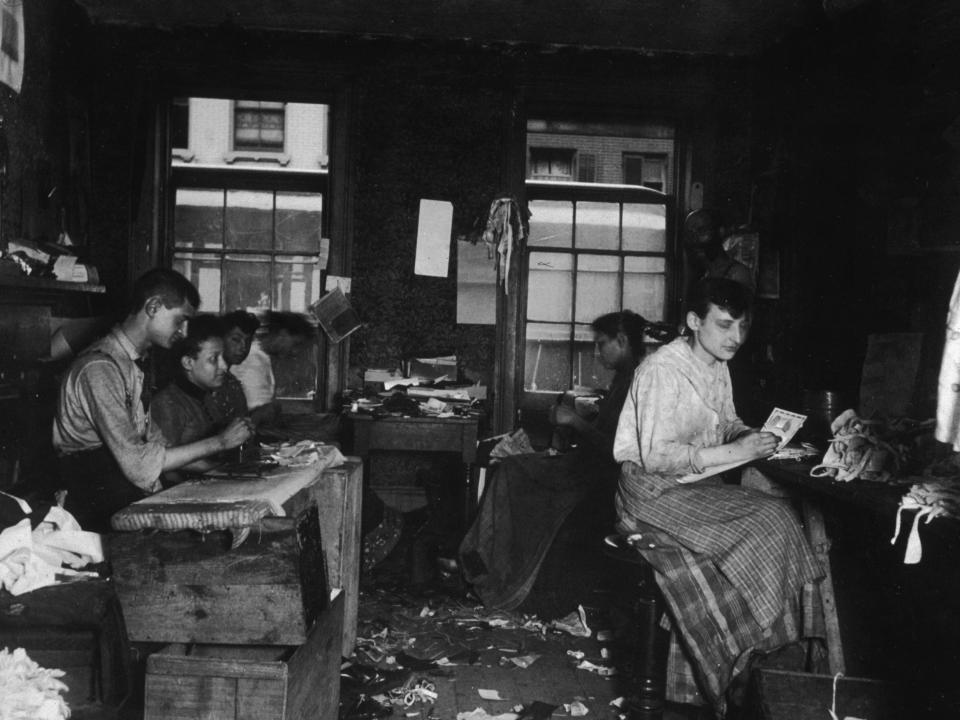 Men and women make neckties inside a tenement in Little Italy, New York City, circa 1890.