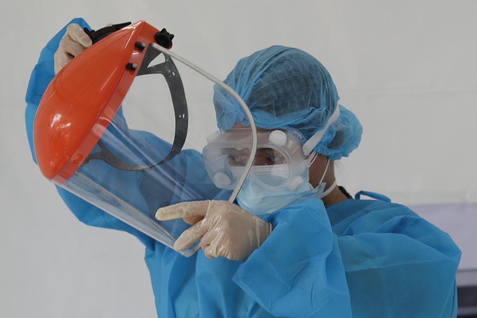 A health worker removes her face shield after performing a rapid tests on residents at a parking lot that has been converted into an extension of the Gat Andres Bonifacio Memorial Medical Center in Manila, Philippines on Monday, Aug. 3, 2020. Philippine President Rodrigo Duterte is reimposing a moderate lockdown in the capital and outlying provinces after medical groups appealed for the move as coronavirus infections surge alarmingly. (AP Photo/Aaron Favila)