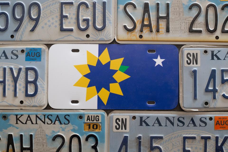 A city of Topeka flag license plate is seen within a mix of current and older Kansas license plates.