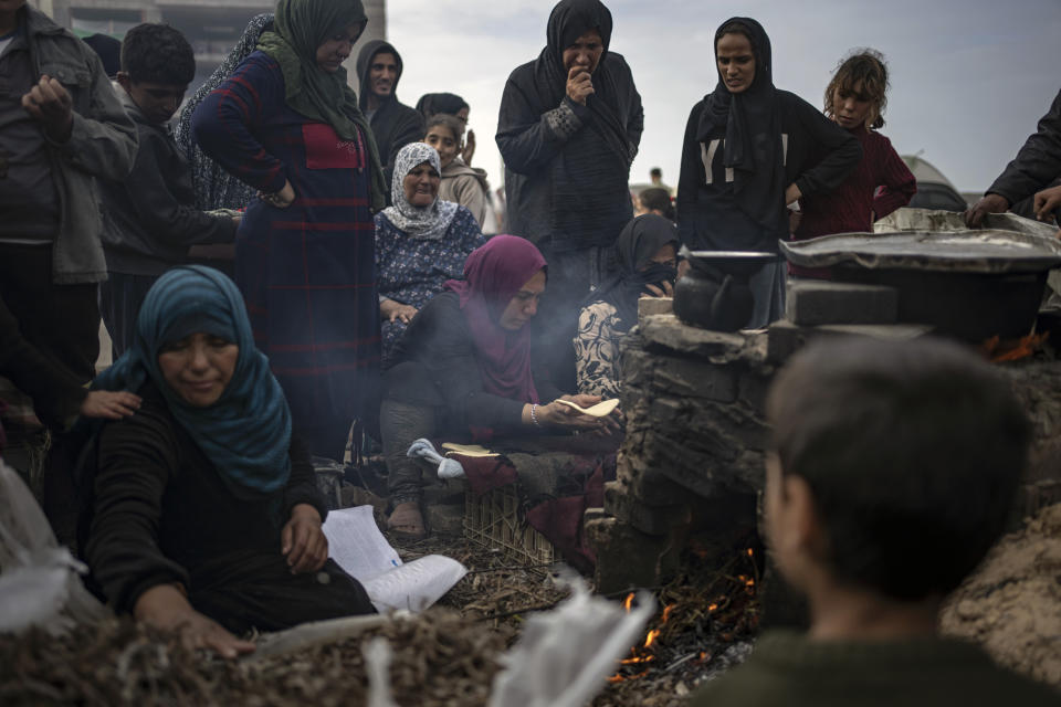 Palestinos desplazados por los bombardeos israelíes esperan su turno para cocer pan en el campamento improvisado en Muwasi, en Rafah, en el sur de Gaza, el 23 de diciembre de 2023. (AP Foto/Fatima Shbair)