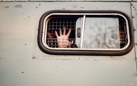 A supporter of the opposition MDC Alliance gestures the party's symbol from inside of a prison truck - Credit: ZINYANGE AUNTONY/AFP/Getty Images