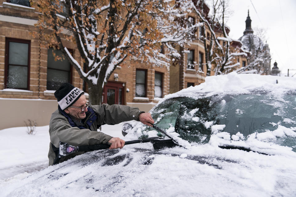 Patrick Costanzo brushes snow off a friend's car on Wednesday, Nov. 27, 2019, in St. Paul, Minn. (Leila Navidi/Star Tribune via AP)