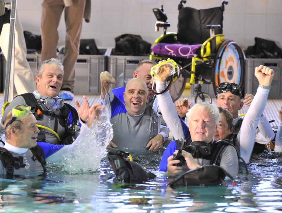 French Philippe Croizon (C), 44, celebrates on January 10, 2013 with a group of 15 Belgian divers after becoming the first quadruple amputee to dive at a depth of 33 meters in the deepest swiming pool in the world in Brussels. He used flippers attached to prosthetic limbs to dive to the bottom of the pool to set a new world record for an amputee. Croizon had all four limbs amputated in 1994 after being struck by an electric shock of more than 20,000 volts as he tried to remove a TV antenna from a roof. He has swum across the English Channel and all five intercontinental channels. AFP PHOTO GEORGES GOBETGEORGES GOBET/AFP/Getty Images