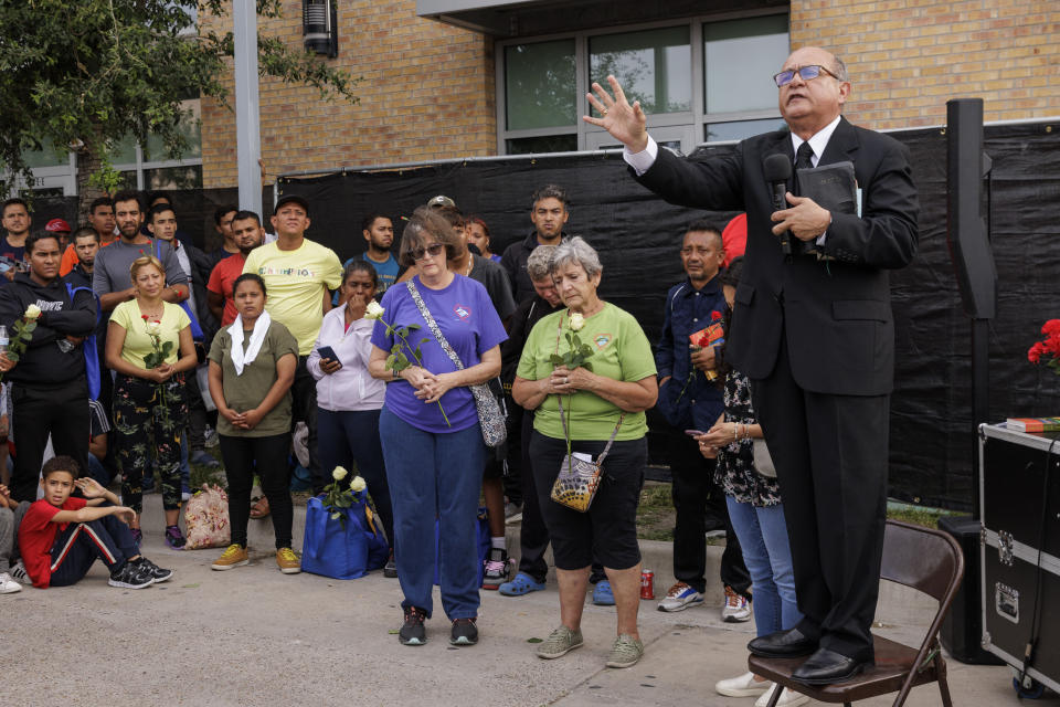 Rev. Carlos Navarro, a local church pastor, speaks to migrants and community members at a vigil for the eight migrants that were killed and several others that were injured the day before while waiting at a bus stop, in Brownsville, Texas, Monday, May 8, 2023. (AP Photo/Michael Gonzalez)