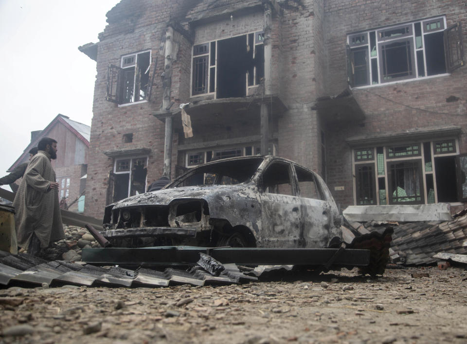 Kashmiri villagers gather near a car and a house that was damaged during a gun battle between government forces and suspected rebels in Bijbehara, some 28 miles (45 kilometers) south of Srinagar, Indian controlled Kashmir, Sunday, April 11, 2021. (AP Photo/Mukhtar Khan)