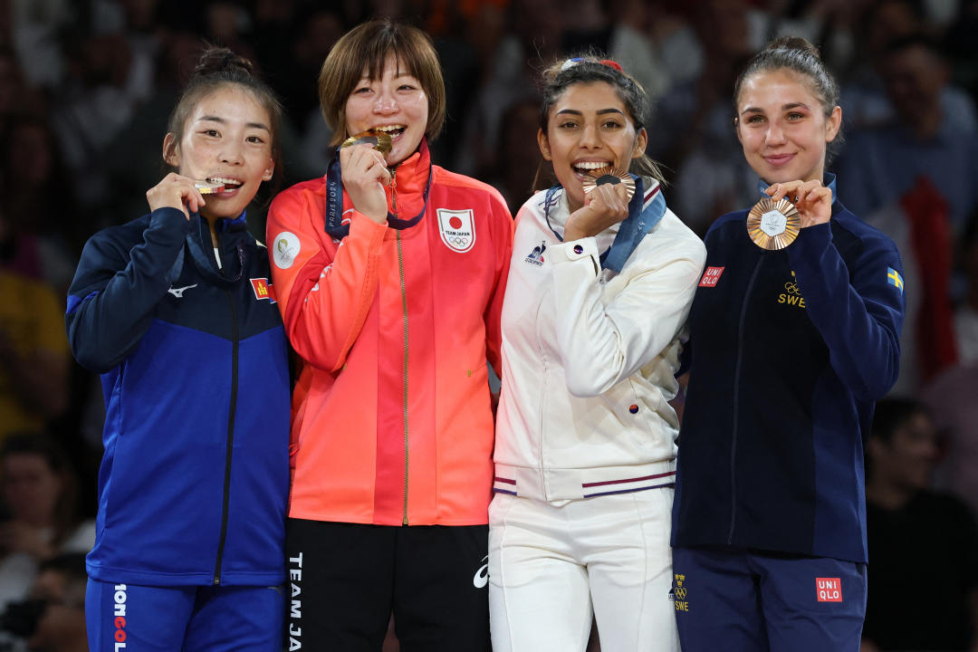 Ganadora de medalla de plata de Mongolia Baasankhuu Bavuudorj, la ganadora de oro de Japaón Natsumi Tsunoda y la ganadora de bronce, de Francia, Shirine Boukli junto con la sueca Tara Babulfath celebran en el podio.  (JACK GUEZ/AFP via Getty Images)