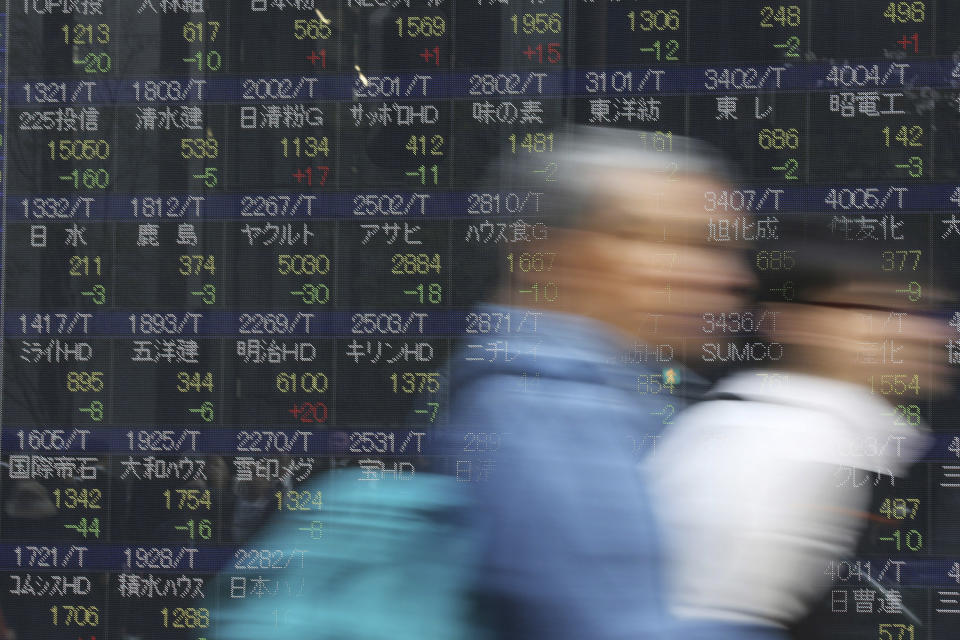 Man walk by an electronic stock price indicator in Tokyo Tuesday, April 8, 2014. Asian stock markets were mixed Tuesday after Japan's central bank refrained from expanding its stimulus and declines in tech stocks weighed on prices. The regional heavyweight, Tokyo's Nikkei 225, shed 201.97 points, or 1.36 percent to close at 14,606.88 after Japan's central bank refrained from expanding its ultra-loose monetary policy. (AP Photo/Eugene Hoshiko)