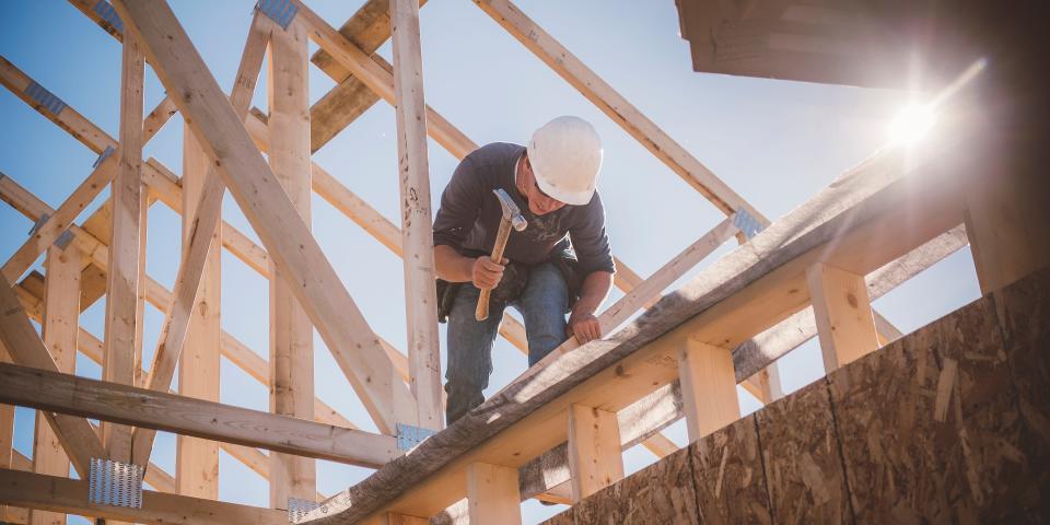 A builder works on a home roof.