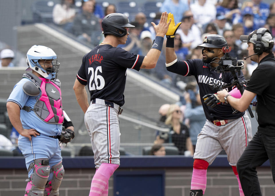 Toronto Blue Jays catcher Alejandro Kirk, left, looks on as Minnesota Twins' Carlos Santana, second from right, is congratulated by Twins' Max Kepler (26) after hitting a three-run home during seventh-inning baseball game action in Toronto, Sunday, May 12, 2024. (Frank Gunn/The Canadian Press via AP)